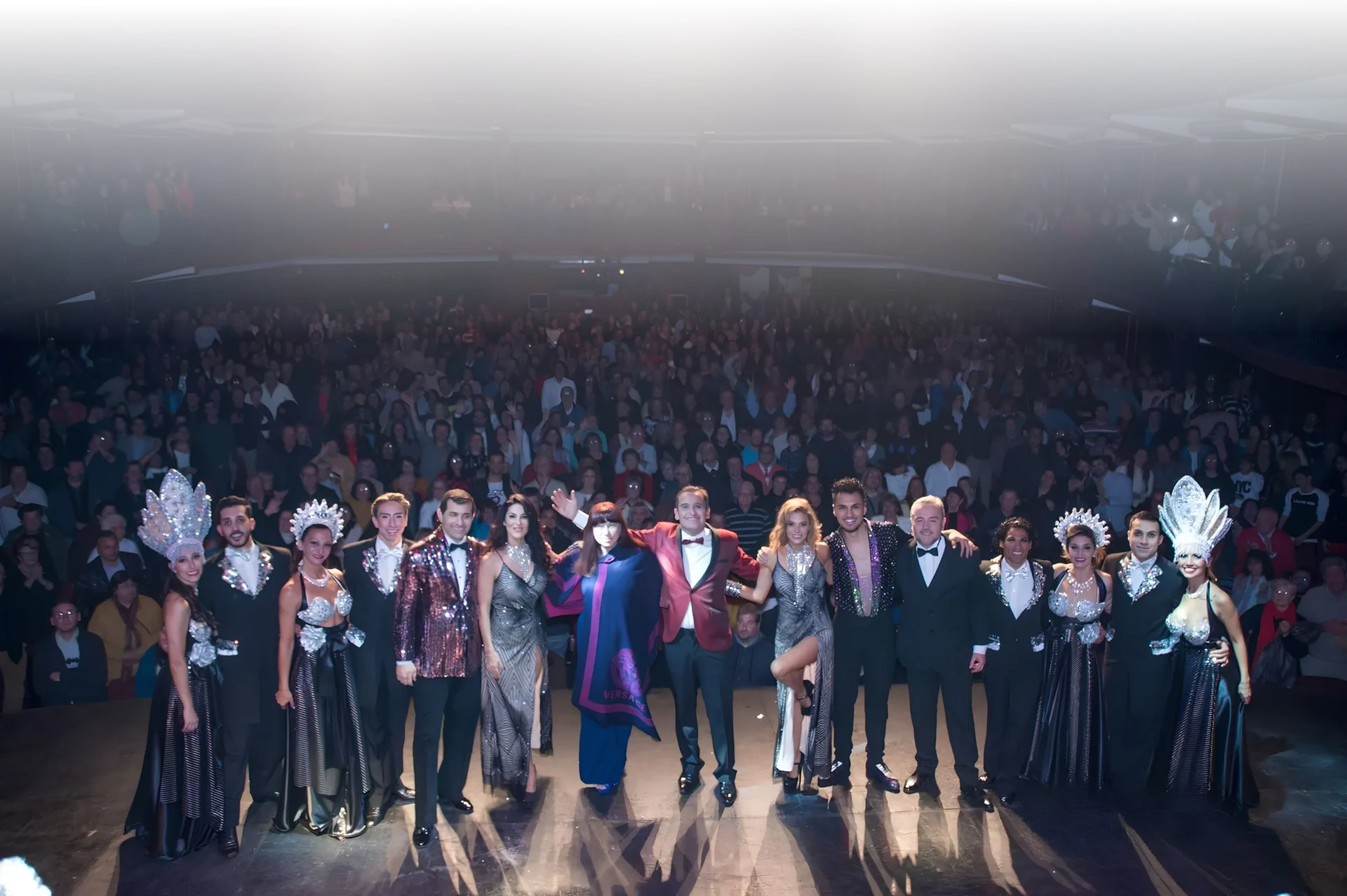 Elenco de Glamorée saludando al público en un teatro colmado