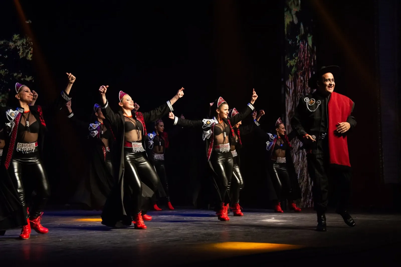 Cuerpo de baile con vestuario negro y rojo en pleno show